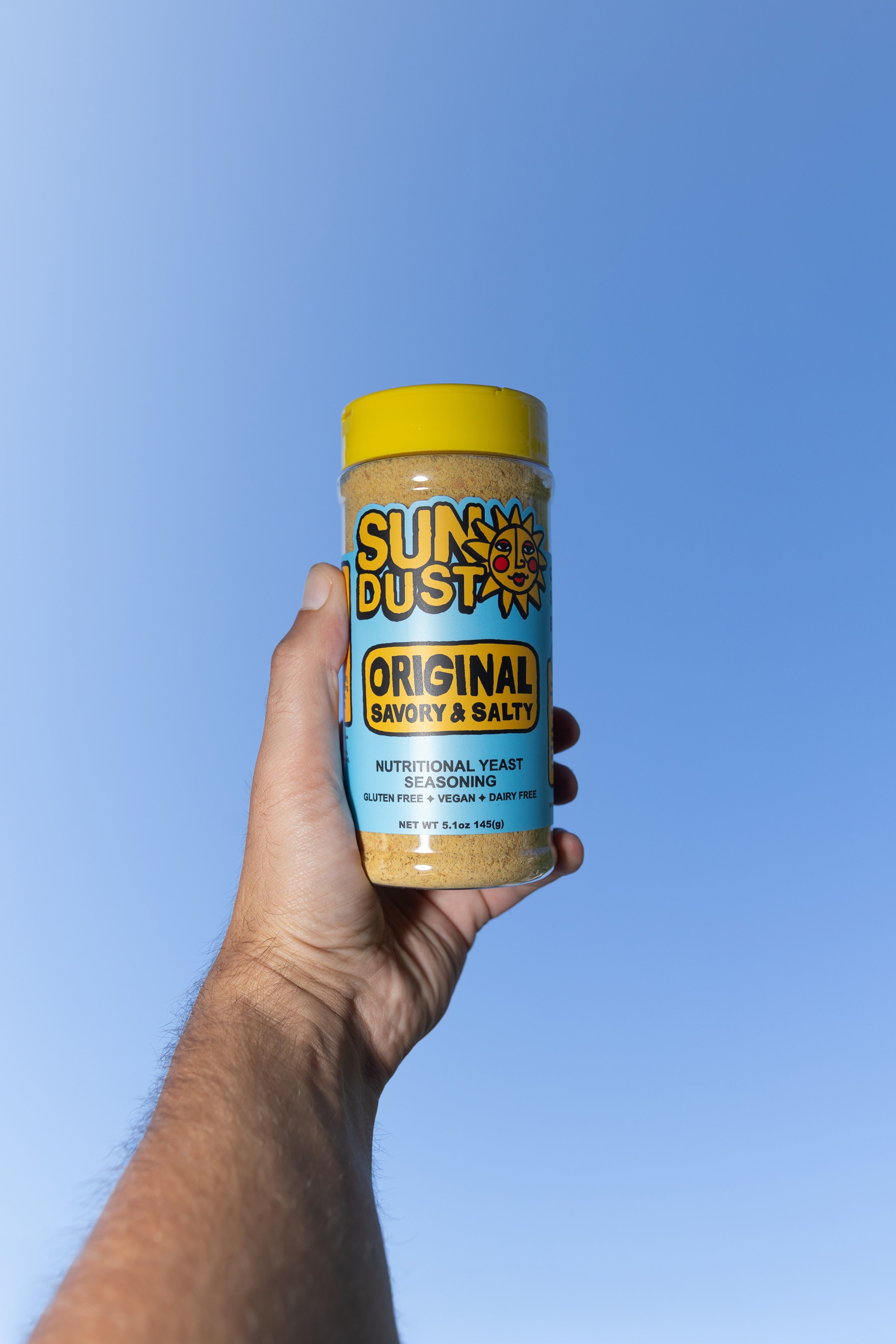 man's hand holding up SunDust Original Bottle